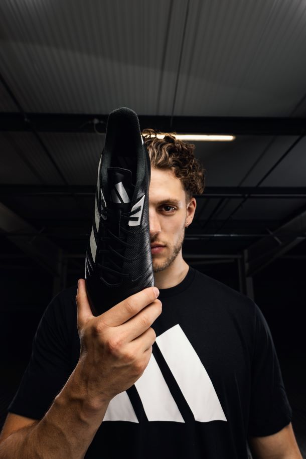 adidas Kakari RS Rugby Boots in Black, held up by Rugby Player wearing adidas Shirt.